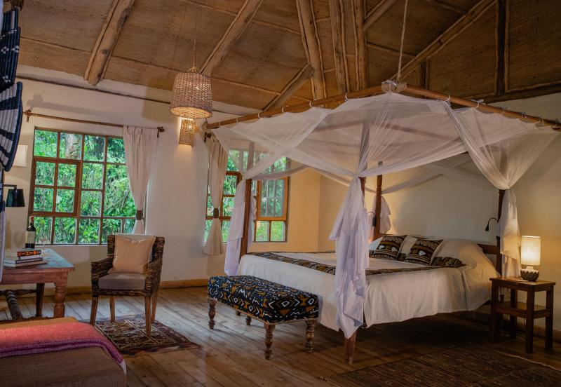 a room with a bed and a chair at Bwindi Lodge
